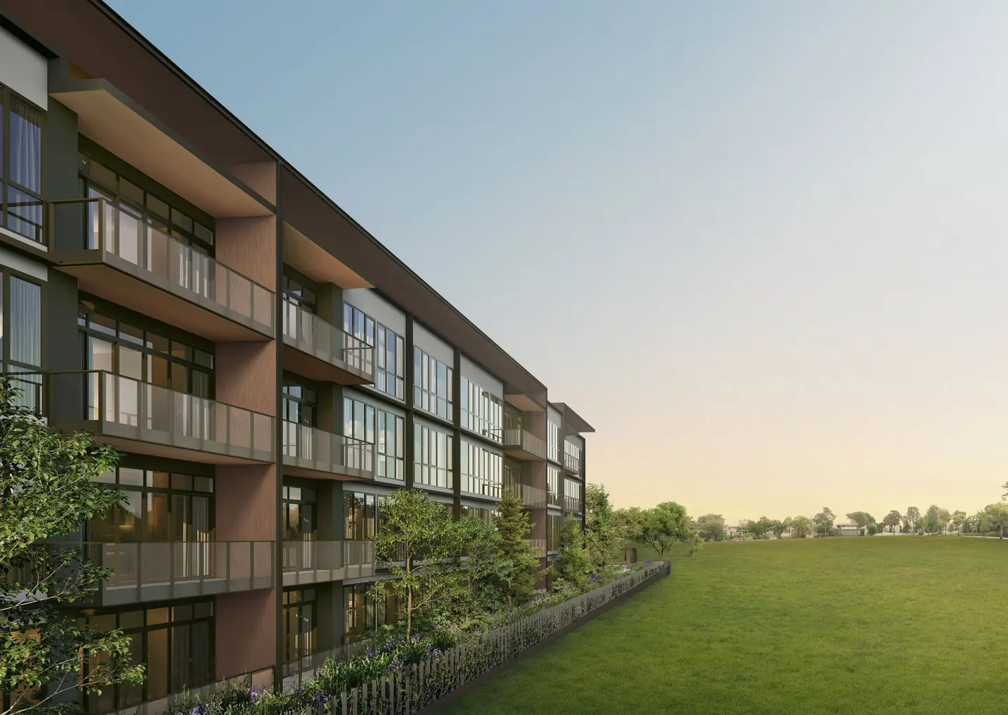 Residential block with deep balconies beside an open lawn at dusk